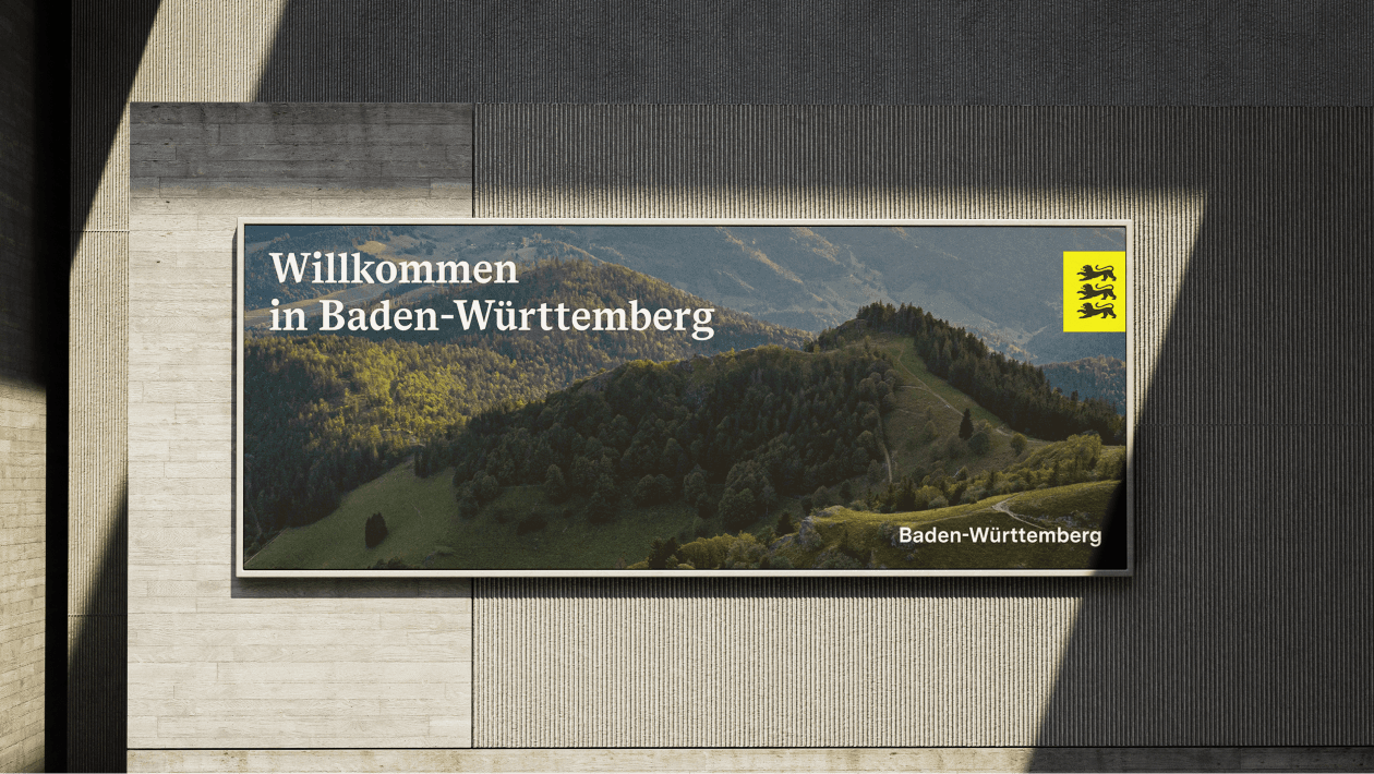 Layoutetes Plakat Willkommen in Baden-Württemberg mit vollformatigem Foto eine waldigen Hügellandschaft.